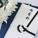 「御香料」と書かれた香典袋と白い菊の花が2輪ある写真