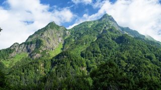 夏の上高地の明神岳。青空と深い緑色の山の写真
